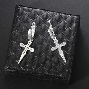 Macro shot of silver cross drop earrings with pavé zircons on black textured jewelry box
