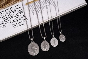 Detail view of four sizes of silver Virgin Mary pendants on stainless steel necklaces