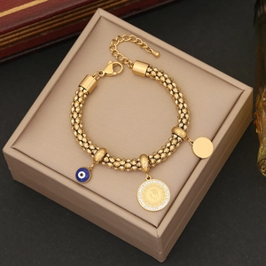 Detail of gold evil eye and coin charms on a stainless steel bead chain bracelet