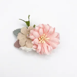 Detailed view of layered pink chiffon daisy hair clip with rhinestone and green fabric leaf