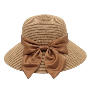 Close-up of a wide-brim straw hat with tight woven texture and a dark brown silk bow
