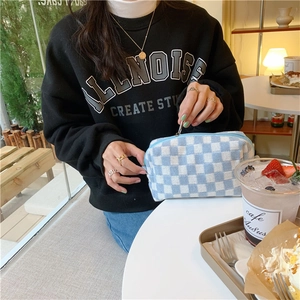 Close-up of blue and white checkered knitted makeup bag with a metal zipper detail