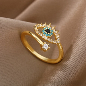 Macro detail of golden evil eye open ring with blue stones on silk fabric