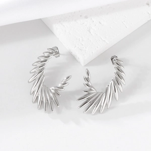 Modern silver wing-shaped stainless steel stud earrings shown on white textured stone