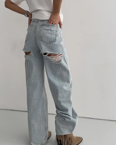 Détail d'un jean bleu clair délavé avec motif déchiré à franges sur la poche arrière