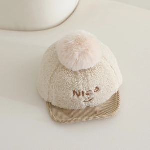 Détail du bonnet d'hiver bébé avec broderie smiley, texture laine et pompon en fourrure
