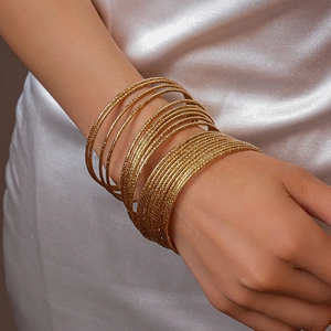 Dettaglio del set di 20 bracciali dorati stratificati con finitura testurizzata su seta