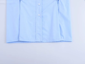 Détail de l'ourlet de chemise bleu clair et boutons blancs sur tissu en coton