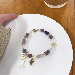 Detalle de pulsera de cuentas con cristales de lavanda, dijes de estrella de mar y concha marina