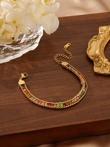 Close-up of golden twist chain bracelet with colorful gradient zircon stones on wood surface