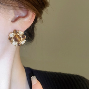 Macro shot of vintage floral stud earrings with brown gems and pearls on a model ear