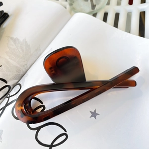 Macro detail of amber tortoise shell hair claw clip on fashion magazine backdrop