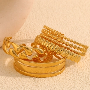 Detailed macro view of 18K gold plated stackable bracelets with diverse textures and finishes