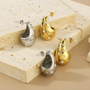 Macro detail of teardrop earrings in gold and silver finish with inlaid clear zircons
