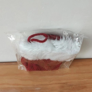 Close-up of a red and white knitted Christmas hat with pom-poms in clear packaging