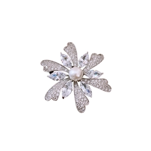 Elegant floral silver brooch with zircon petals and a white pearl center on white background
