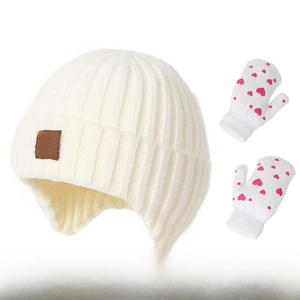 Close-up of knit winter earflap hat and matching pink heart pattern gloves for toddlers