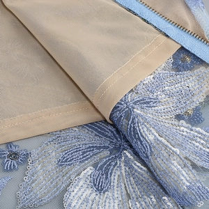 Detail der blauen Blumenstickerei mit weißen Pailletten auf feinem Netzstoff des Abendkleids