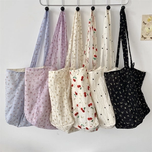 Collection of floral print tote bags in pleated fabric hanging against a white wall