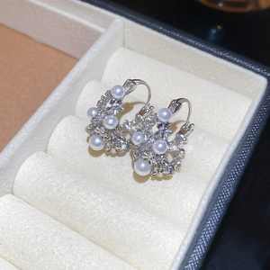 Detailed view of silver flower earrings with white pearls in a beige velvet jewelry box