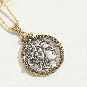 Close-up of vintage bimetal pharaoh pendant with twisted gold chain on white leather