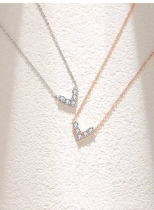 Macro view of V-shaped zircon pendant necklaces in silver and rose gold finishes