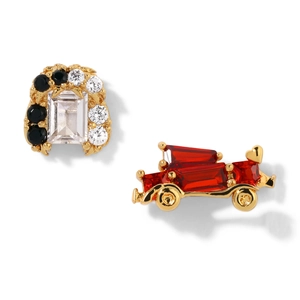 Macro view of asymmetrical gold-plated stud earrings with red gems and black zircons