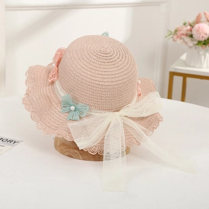 Detailed view of pink straw hat featuring lace trim, mesh bow, and pearl butterfly embroidery