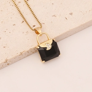 Macro shot of gold necklace with black handbag-shaped pendant and zircon accents