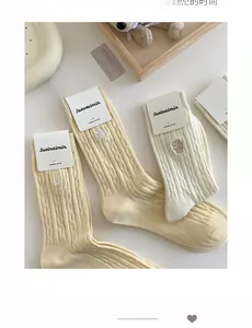 Détail de la texture côtelée en coton peigné et broderie sur chaussettes crème