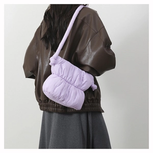 Quilted light purple puffer bucket bag with knotted strap detail shown on shoulder