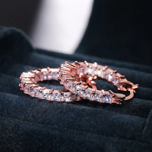Macro detail of rose gold hoop earrings with claw-set square cubic zirconia on velvet