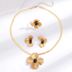 Detailed flat lay of golden flower jewelry set with necklace, ring and earrings