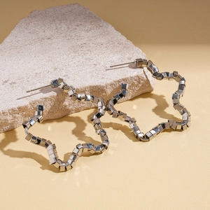 Macro shot of silver cube chain star earrings on natural stone with geometric shadows