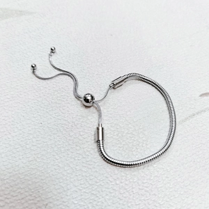 Detail of adjustable silver snake chain bracelet with sliding bead clasp on white texture