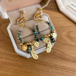 Detailed shot of bohemian feather and turquoise pendants on gold-plated earrings