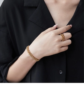 Close-up of a gold multi-strand beaded bracelet and ring set on model wearing black shirt