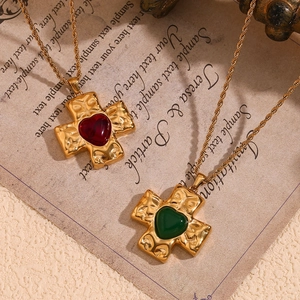 Detail of 18K gold plated cross pendant with red and green heart gems on a twisted chain