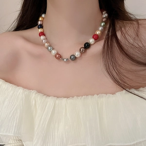 Close-up of colorful pearl necklace on model showing elegant beads and metal clasp