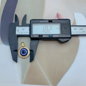 Macro shot of gold evil eye pendant diameter measurement with digital caliper tool