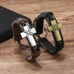 Detail of vintage leather bracelets with metal cross pendants and adjustable knots