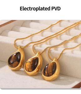 Close-up of three 18k gold plated PVD necklaces with tiger eye pendants in a jewelry box