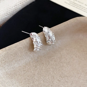 Macro detail of silver screw-thread earrings with sparkling crystal pavé inlay