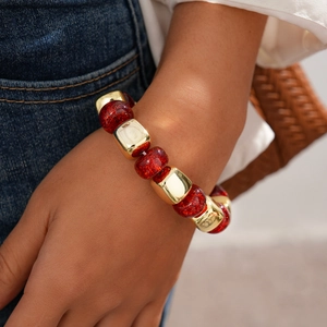 Close-up of beaded bracelet with red glitter acrylic and golden square metal accents