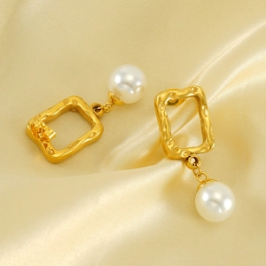 Detail of vintage gold square metal earrings with lustrous round white pearls on silk