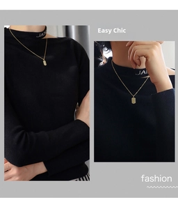 Detail view of the gold-plated square initial pendant necklace on a black sweater