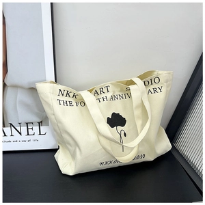 Detailed view of canvas tote bag with black floral print and NKK Art Studio lettering