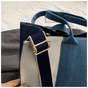 Detail of adjustable gold buckle and wide blue fabric strap on canvas tote bag