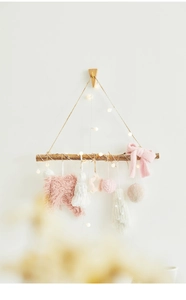 Detailed close-up of pink and white plush ornaments on a rustic wooden branch