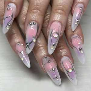 Macro view of long stiletto nails with pink-purple gradient, silver lines and gems
